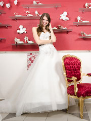 Braut im weißen Hochzeitskleid vor dem Schuhregal